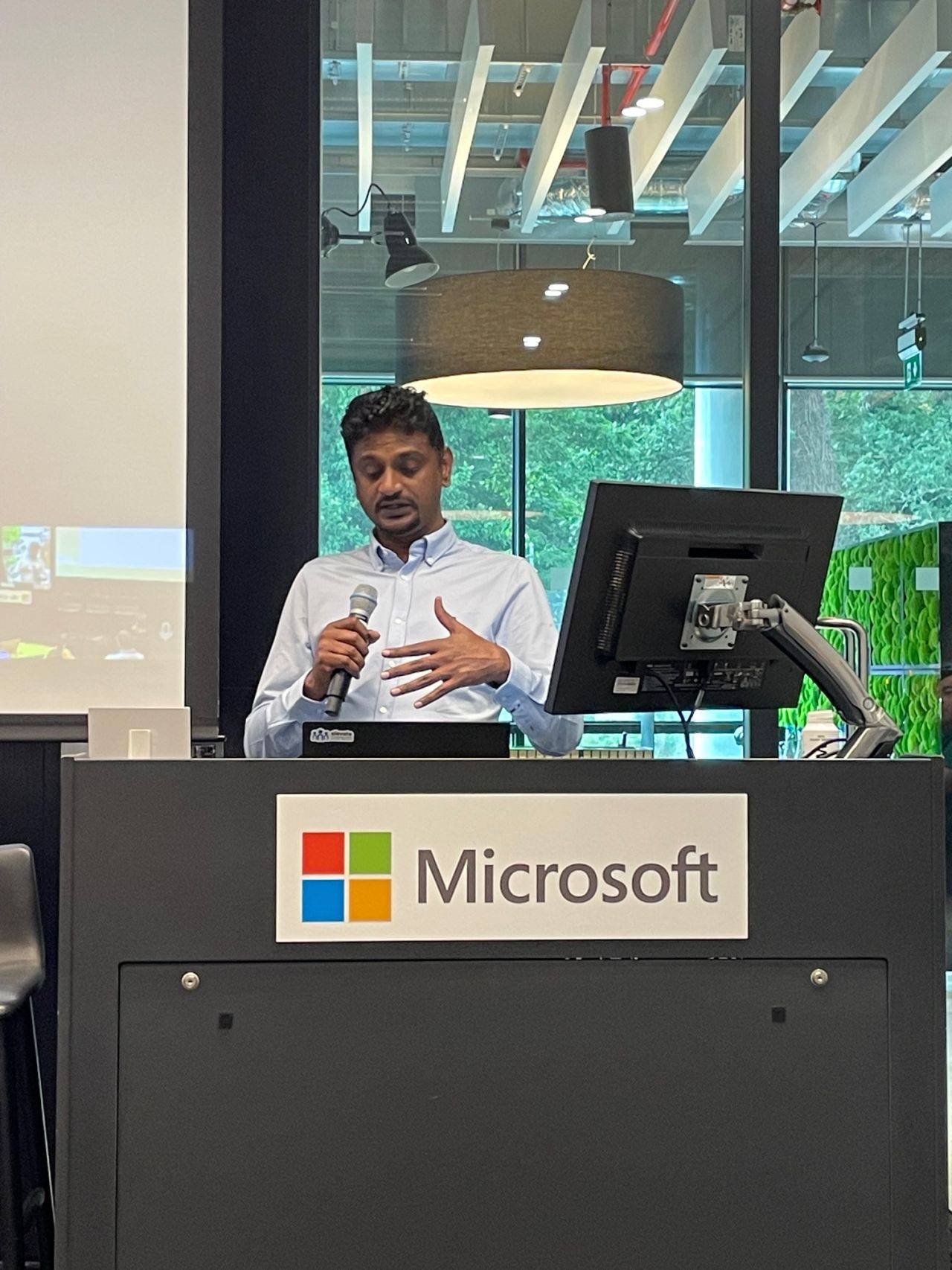 Palanikumar speaks into a microphone from a lectern during a technical presentation.
