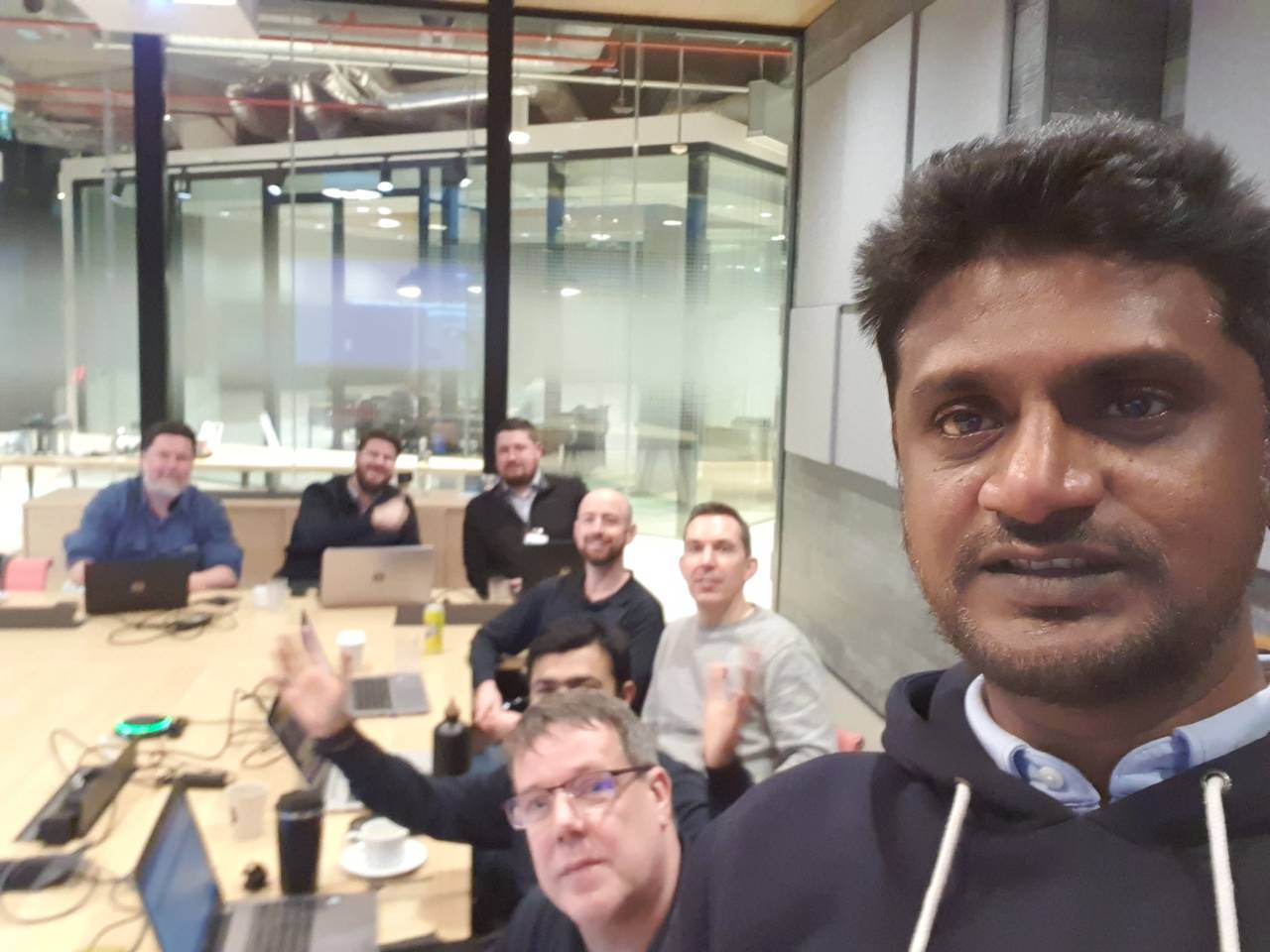 Palanikumar with a group of participants working on laptops around a table in a training room.